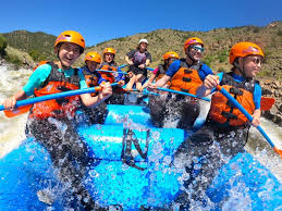 Group in raft laughing as water splashes around them