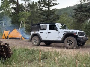 white jeep next to tent in the woods