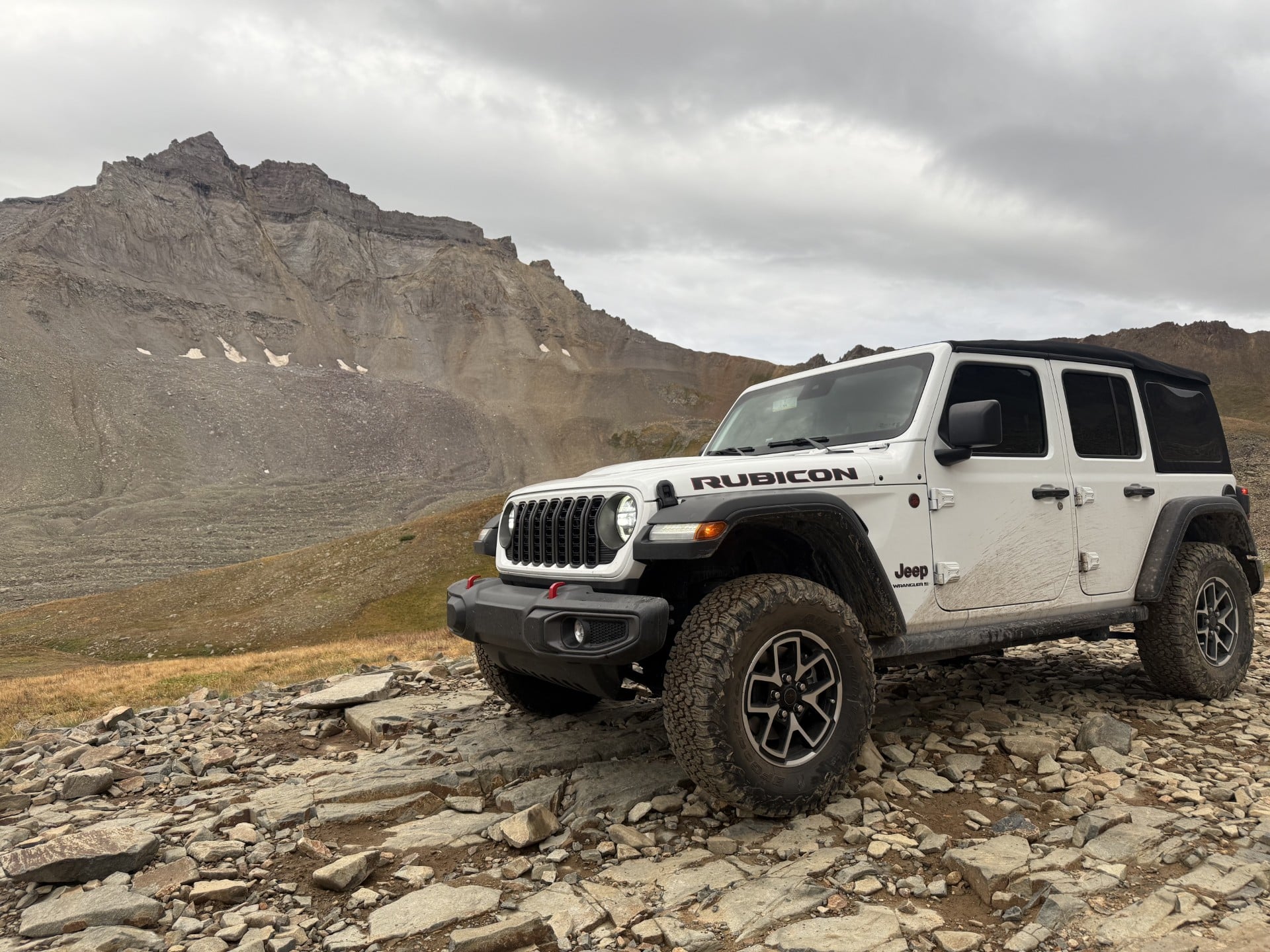 white jeep on rocks in front of mountain 